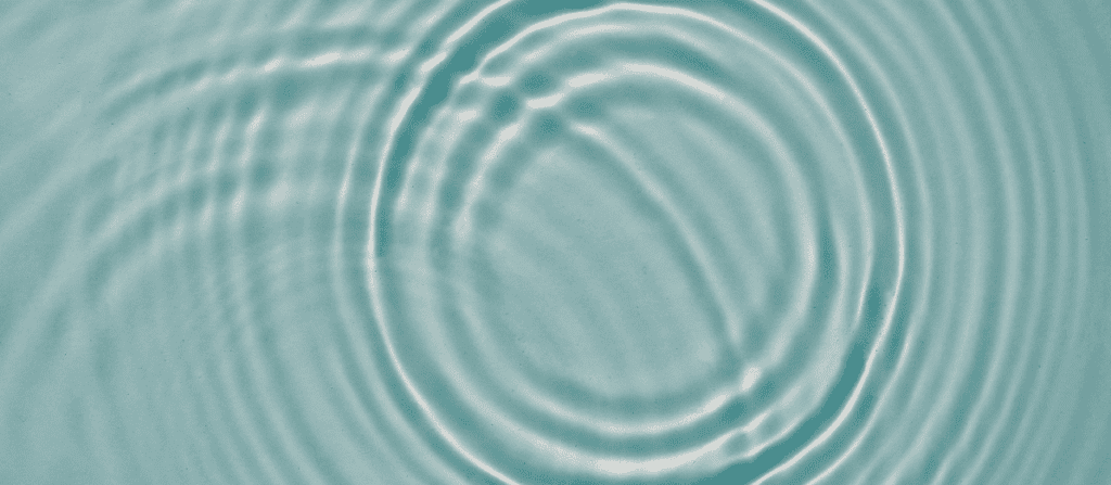 Soft ripples spreading across calm teal water, reflecting light and creating a peaceful, balanced atmosphere