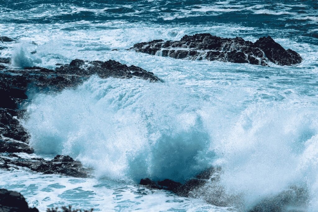 Powerful ocean waves crashing against dark coastal rocks